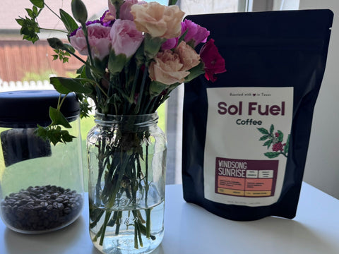 Bouquet of flowers in a jar with Sol Fuel coffee package on a table.